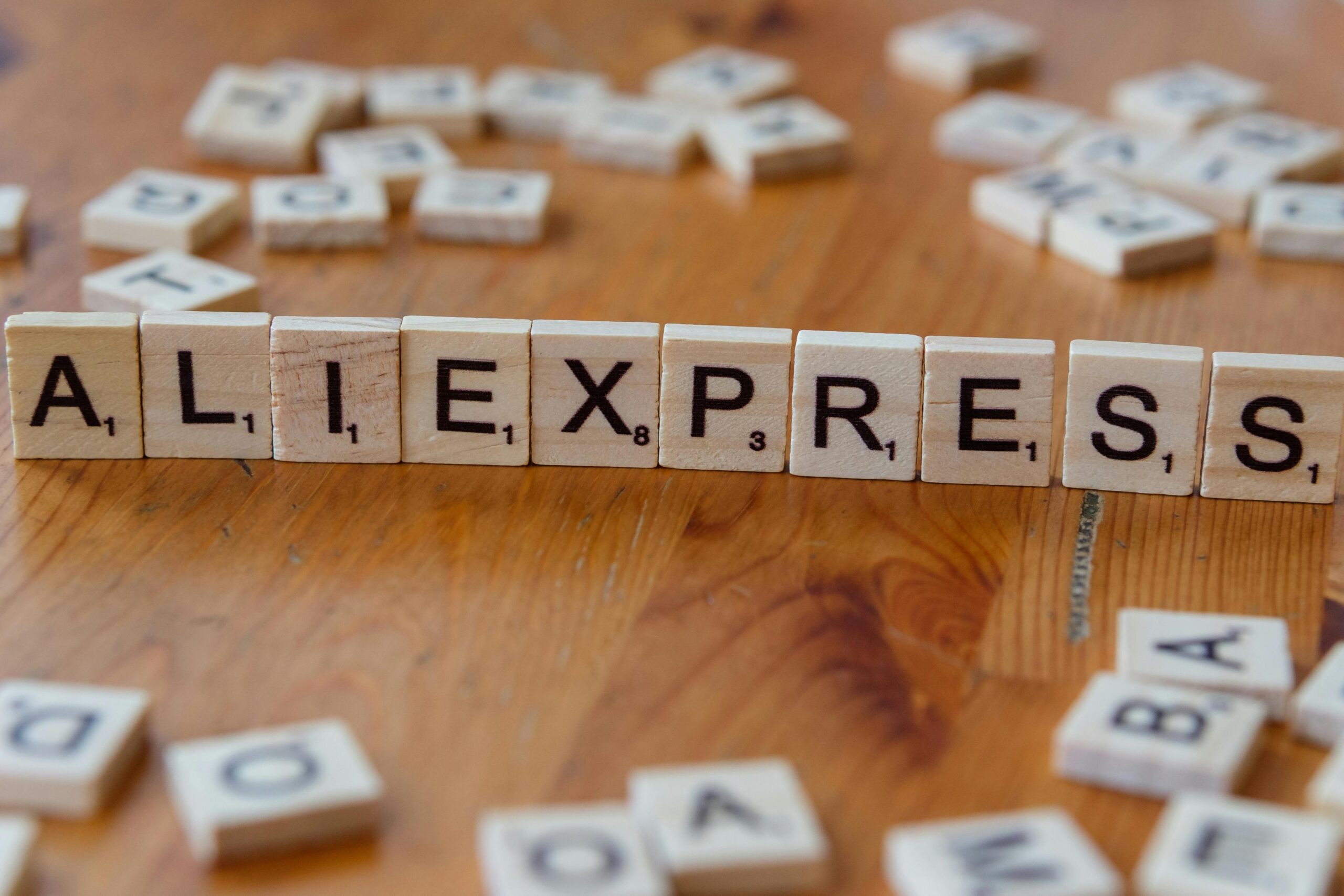 Close-up of Scrabble tiles forming AliExpress on a wooden surface, ideal for ecommerce and retail themes.